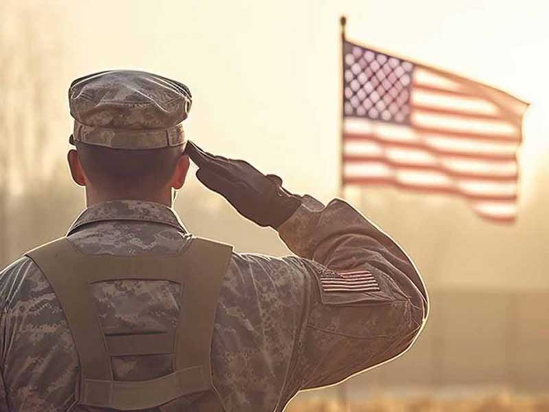 Military personnel saluting the American flag in the background